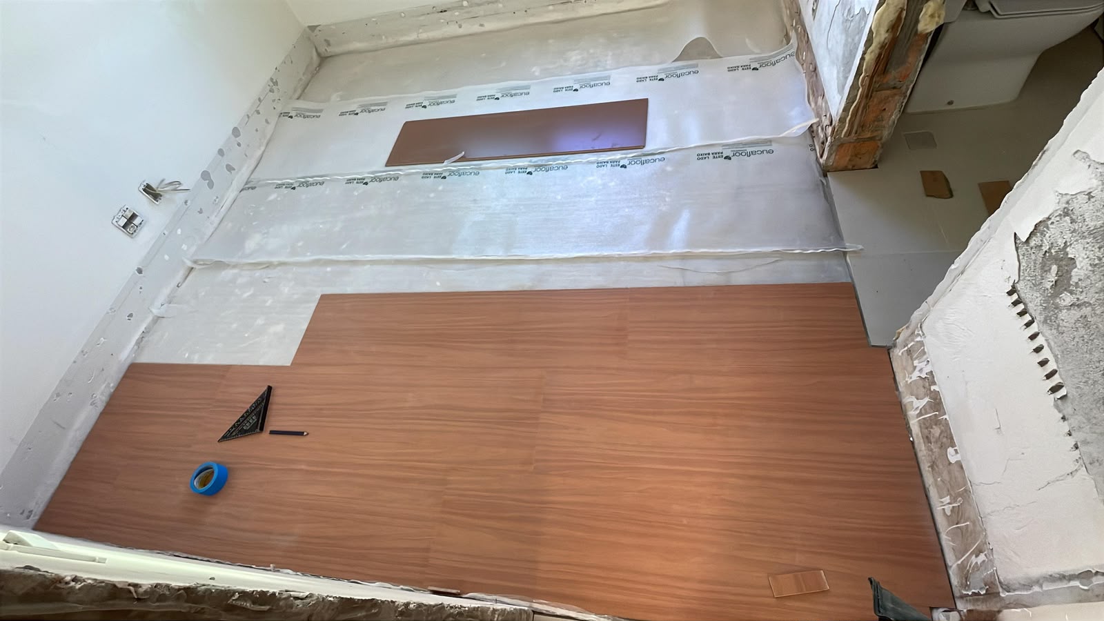 Instalação do piso laminado em andamento — corte e assentamento das réguas.