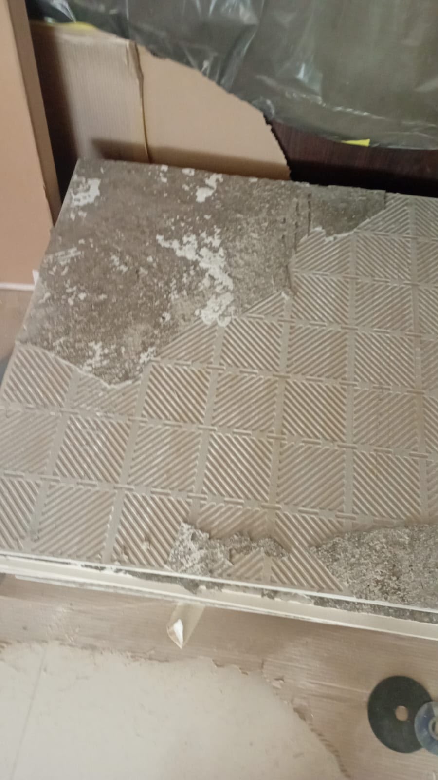 Detalhe do porcelanato removido com argamassa aderida.