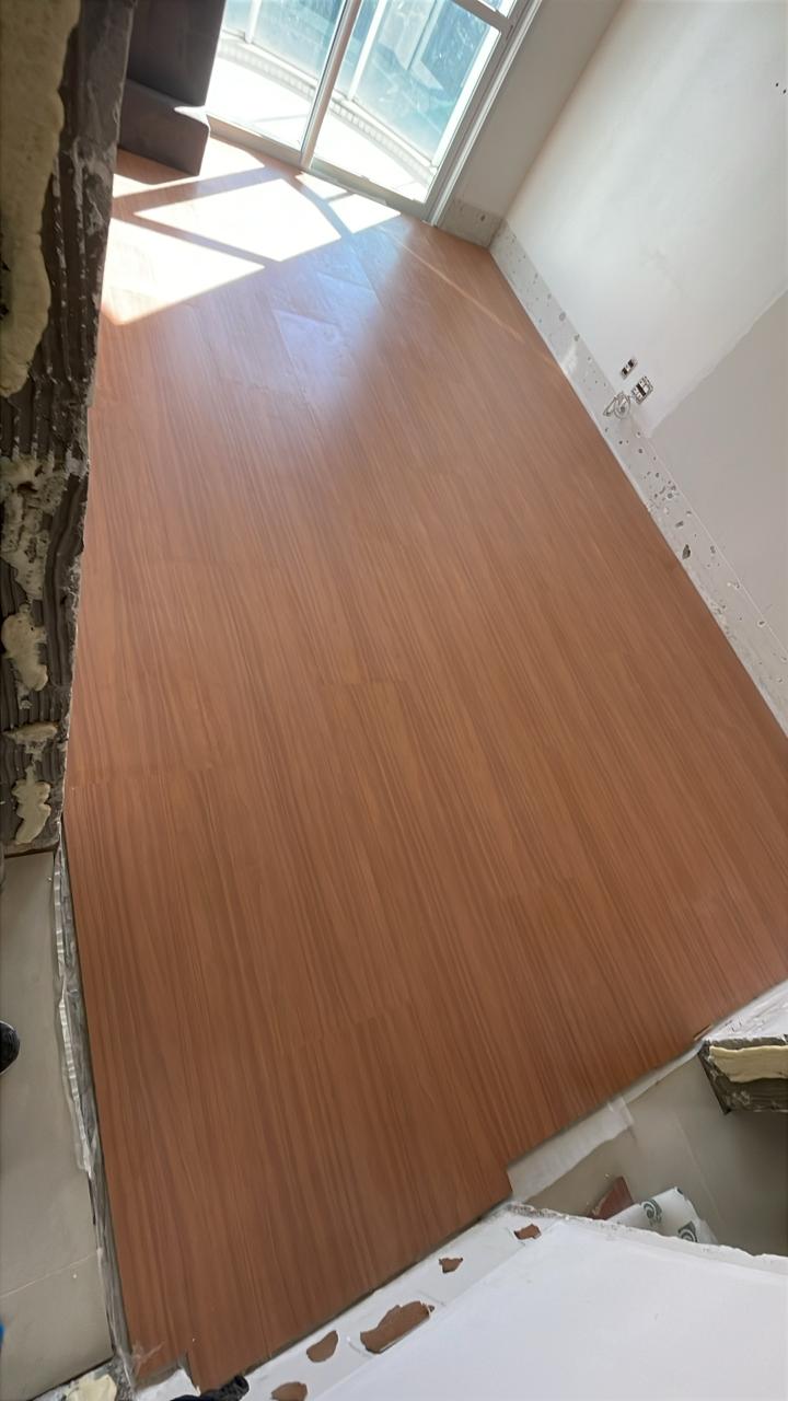 Piso laminado em finalização — ambiente com vista para a sacada.